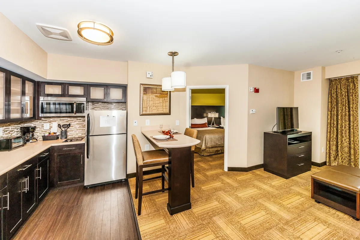 The image displays an open-concept living area that includes a kitchen with bar seating and a comfortable lounge space. The living area features a sleeper sofa and is decorated in an inviting style, perfect for relaxing, entertaining, or accommodating extra guests.