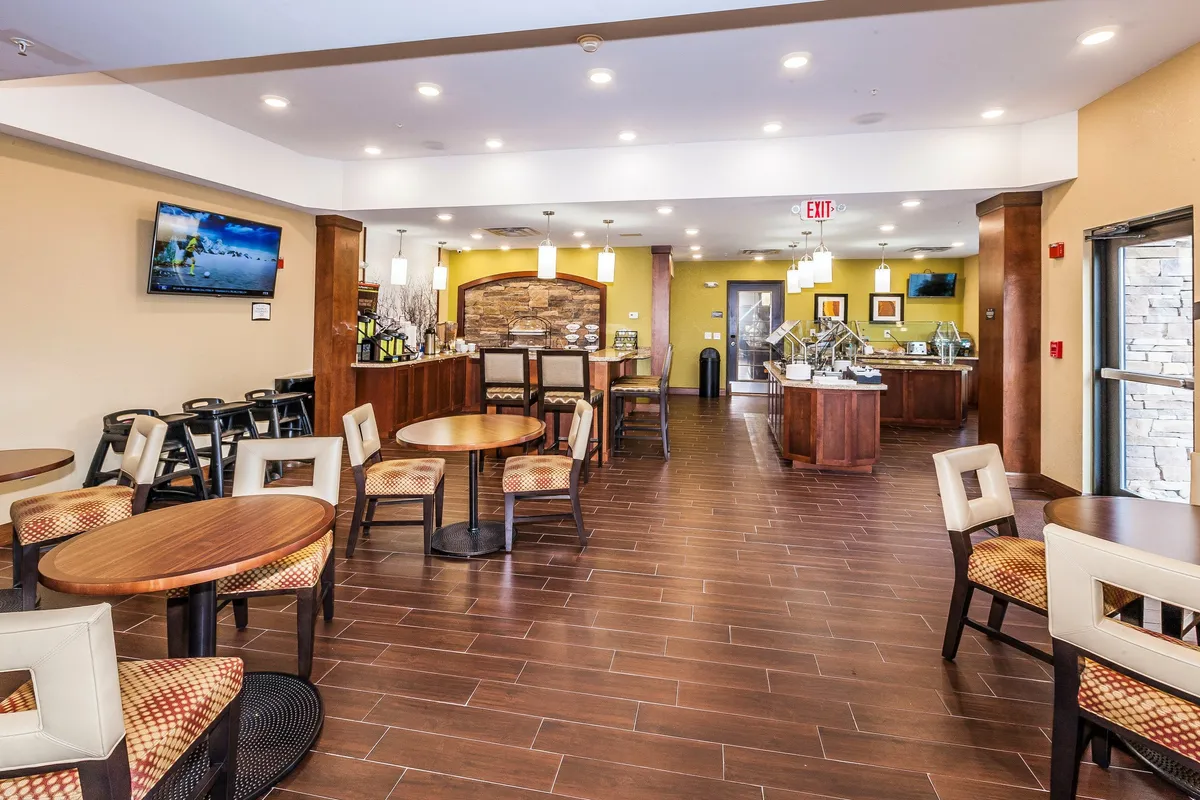 A spacious interior with a central seating area, casual dining tables, and a decorative stone wall. Guests are engaged in social gatherings, casually dining, and sharing stories over coffee in an inviting, relaxed setting.